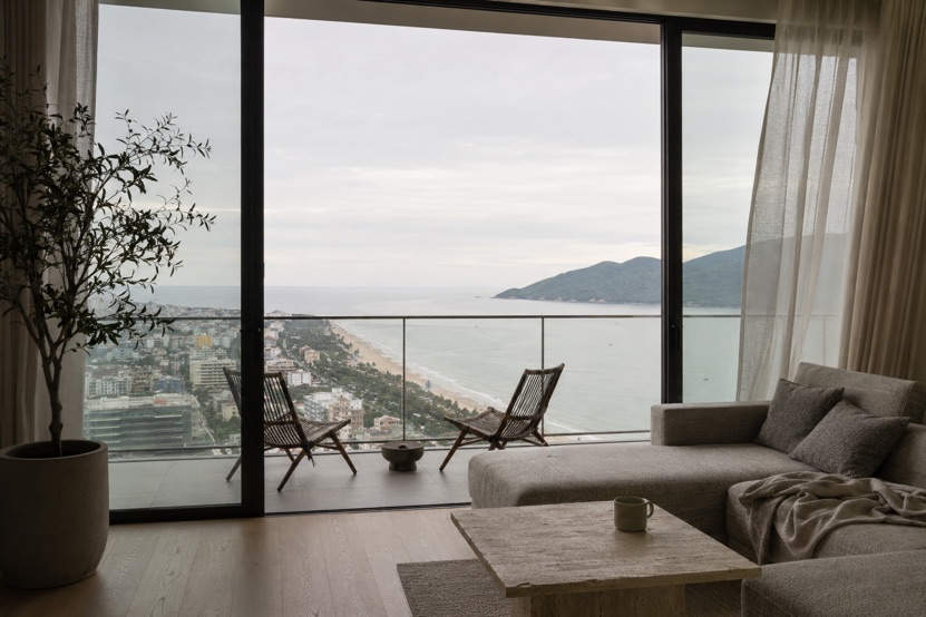 The living room of a high floor sea view apartment in Da Nang, looking north along My Khe beach toward the Son Tra peninsula