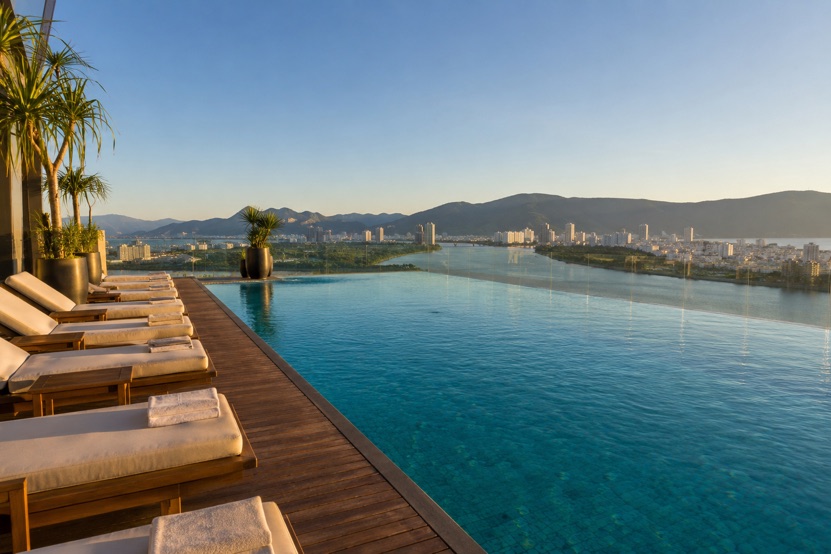 A rooftop infinity pool on a high floor of an apartment building in Da Nang, looking out over the river, the city and the mountains