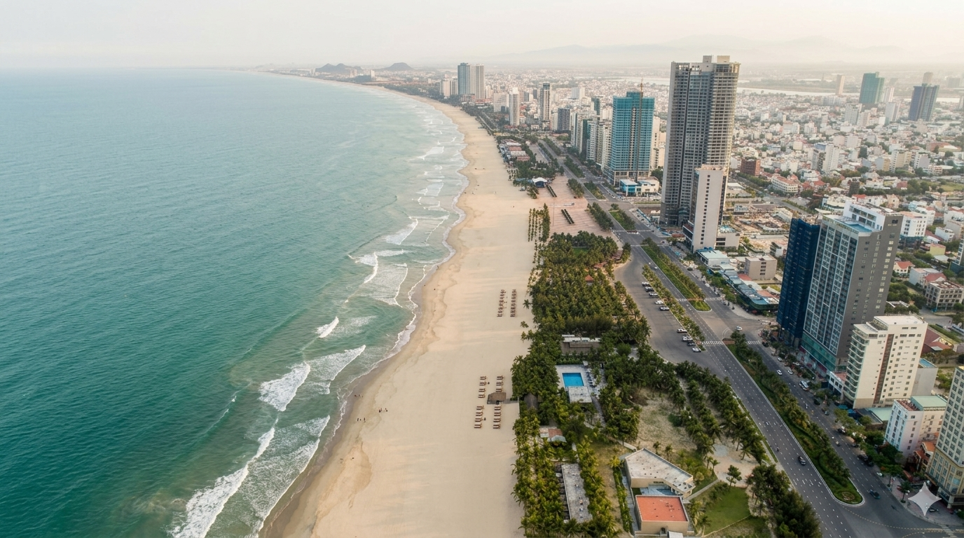 Aerial view of Đà Nẵng coastline with turquoise ocean, white sand beach, and city skyline